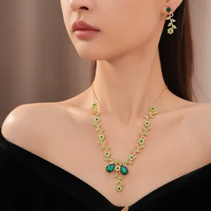 Primo piano di un set di gioielli vintage con fiori di strass verdi e collana di foglie su modella asiatica.