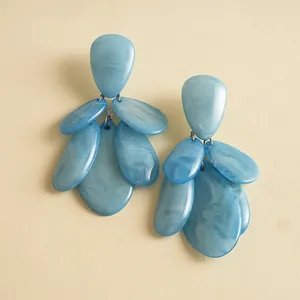 Detail showing the unique marbled texture and layered waterdrop shape of blue resin earrings.