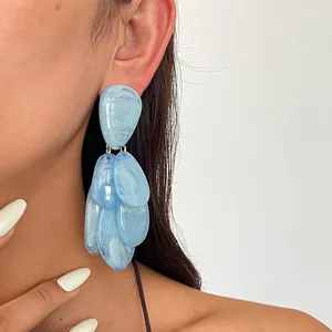 Close-up detailed view of blue marbled resin teardrop tassel earrings worn by a model