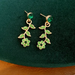 Dettaglio ravvicinato di orecchini vintage oro con fiori di strass verdi