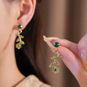 Vista dettagliata di orecchini vintage dorati con fiori e foglie in strass verdi