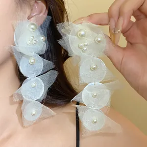 Close-up view of elegant long white chiffon circular drop earrings with pearl embellishments