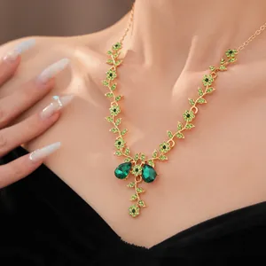 Dettaglio ravvicinato di una collana vintage con fiori e foglie in cristallo verde e oro