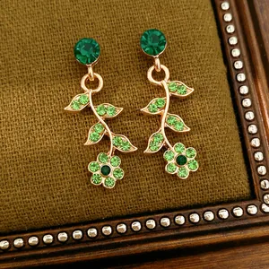 Dettaglio di orecchini vintage dorati con cristalli verdi e design a foglie eleganti