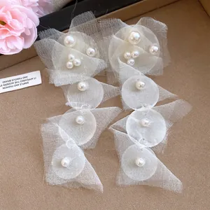 Detailed close-up of elegant chiffon pearl tassel earrings with geometric lace fabric