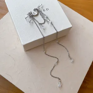 Boucle d'oreille manchette argentée avec glands en cristal sur boîte cadeau