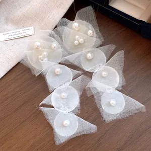 Detailed view of white chiffon mesh earrings decorated with lustrous artificial pearls.