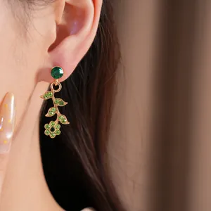 Dettaglio ravvicinato di un orecchino vintage a fiore e foglia con strass verdi brillanti