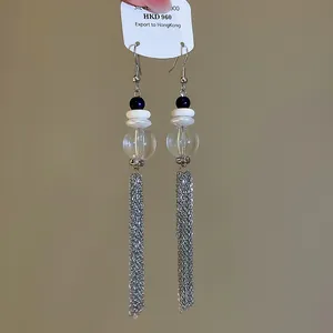 Gros plan détaillé de boucles d'oreilles à pompon argenté avec perles de cristal bleu.