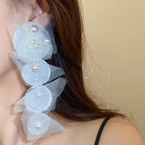 Detailed close-up view of white chiffon circle earrings with pearls worn by a model