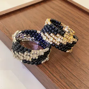 Detail van meerlaagse kralenarmband met fonkelende strassteentjes en zwarte parels op hout