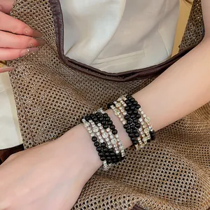 Gedetailleerd overzicht van gestapelde armbanden met zwarte kralen en glanzende strass.