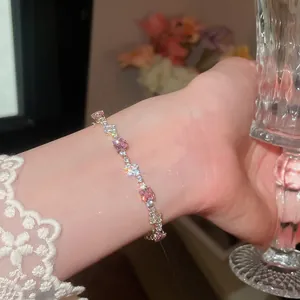 Nahaufnahme eines funkelnden rosa Zirkonia-Armbands am Handgelenk mit Spitzenärmel