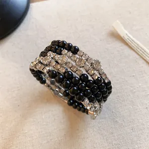Detailopname van meerlaagse armband met strassteentjes en zwarte acryl kralen.