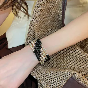 Detail van een elegante meerlaagse kralenarmband met strass en zwarte kralen om de pols.
