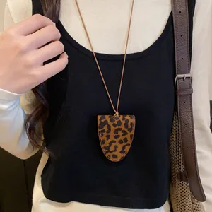 Modische Halskette mit Leopardenmuster-Anhänger und brauner Lederschnur am Modell.