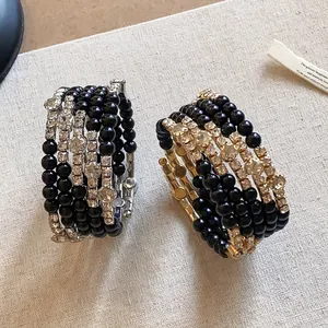 Gedetailleerde weergave van gelaagde zwarte kralenarmbanden met fonkelende strass.