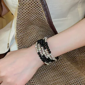 Close-up van meerlagige zwarte kralenarmband met glinsterende strass-bandjes om de pols