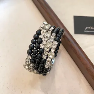 Detailopname van een elegante meerlaagse armband met zwarte kralen en strasstenen.