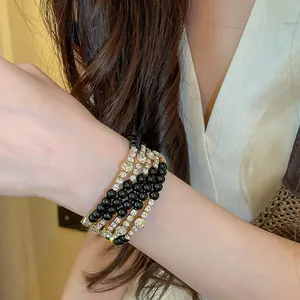 Detailweergave van een meerlagige armband met zwarte kralen en stras om een pols
