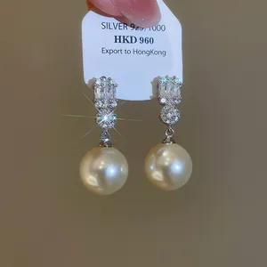 Dettaglio ravvicinato di orecchini di lusso con zirconi e perle con un elegante riflesso.