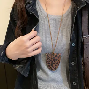 Detailansicht einer Brillenclip-Halskette mit Leopardenmuster auf grauem Pullover