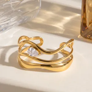 Detail van een golvende roestvrijstalen armband met 18K gouden plating en druppelvormige zirkoon