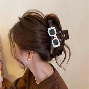 Detailed view of brown acrylic hair claw clip with polka dot sunglasses decor on model