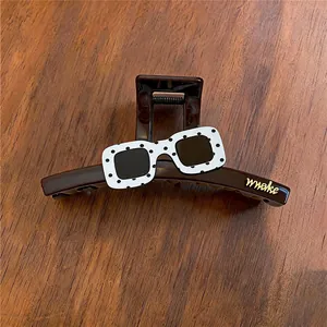 Detailed view of brown acrylic hair claw clip with stylish polka dot sunglass decoration