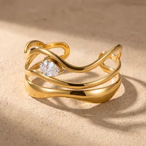 Gedetailleerde close-up van een golvende vergulde armband met peervormige zirkoon