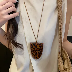 Nahaufnahme einer Halskette mit Brillenhalter aus Leder mit Leopardenmuster auf Creme