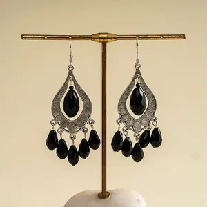 Close-up of bohemian silver-tone earrings with black teardrop acrylic tassels