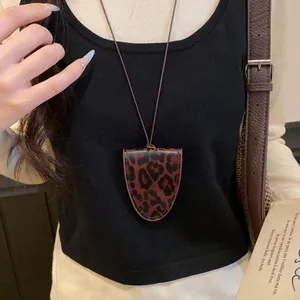 Nahaufnahme einer Lederkette mit Leopardenmuster auf einem schwarzen Stricktop