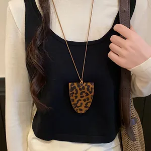 Detailansicht der Halskette mit Leopardenmuster-Anhänger auf Schwarz-Weiß-Outfit