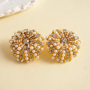 Gros plan d'élégantes boucles d'oreilles fleur avec perles et strass brillants