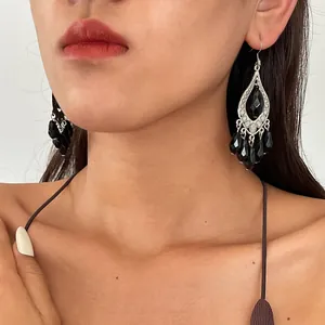 Close-up of black acrylic teardrop tassel earrings with vintage dark style worn by a model