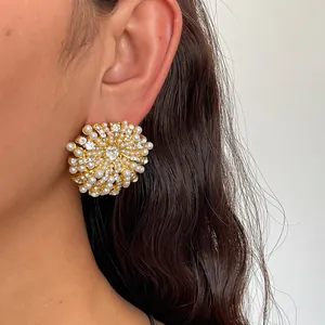 Gros plan de boucles d'oreilles fleur élégantes avec perles blanches et cristaux brillants.