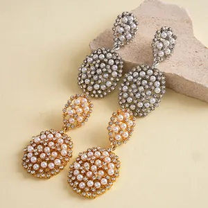 Détail de boucles d'oreilles ovales exquises avec perles et strass en finitions or et argent