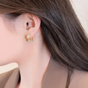 Detail view of 14k gold plated twisted earrings featuring pavé-set zircons on a model
