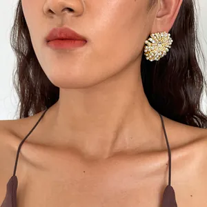Gros plan d'une élégante boucle d'oreille fleur en or avec perles et strass sur modèle