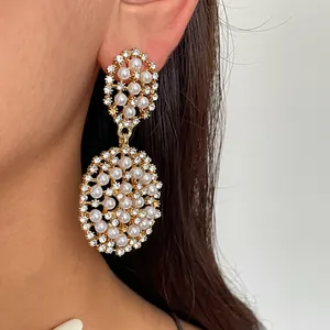 Gros plan d'exquises boucles d'oreilles ovales dorées avec strass et perles