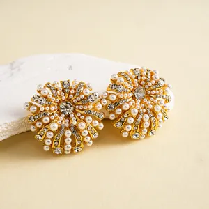 Vue détaillée de boucles d'oreilles fleurs dorées avec perles et strass brillants