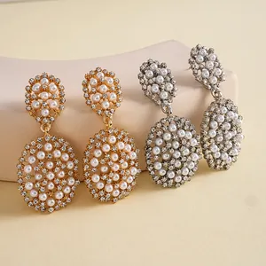 Vue détaillée des boucles d'oreilles ovales dorées et argentées avec perles.