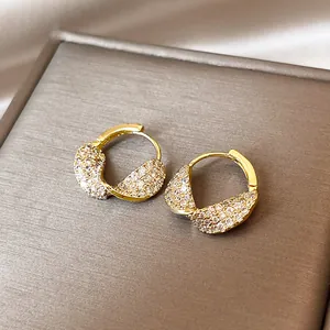 Detailed view of 14k gold-plated twisted hoop earrings with micro-pave clear stones.
