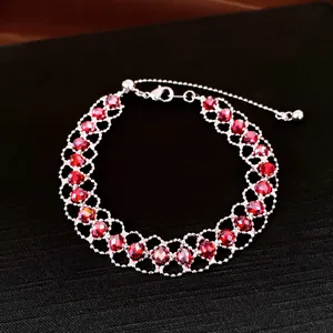 Detailansicht eines geflochtenen Silberarmbandes mit facettierten roten Kristallperlen