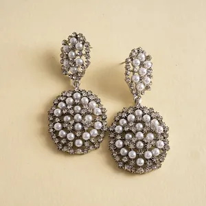Gros plan de boucles d'oreilles argentées élégantes avec des grappes de perles et strass.