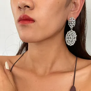 Gros plan de boucles d'oreilles pendantes ovales avec perles et strass sur un modèle