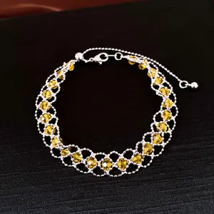Detail des gewebten Silbernetz-Armbands mit leuchtend gelben Kristallen und Karabiner.
