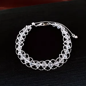 Detailansicht eines silbernen Perlenarmbands mit Kristallakzenten auf dunklem Stoff