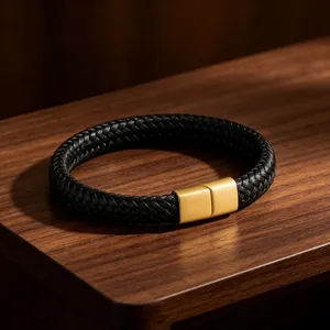 Handgemaakte zwarte gevlochten leren herenarmband met matgouden magnetische sluiting.